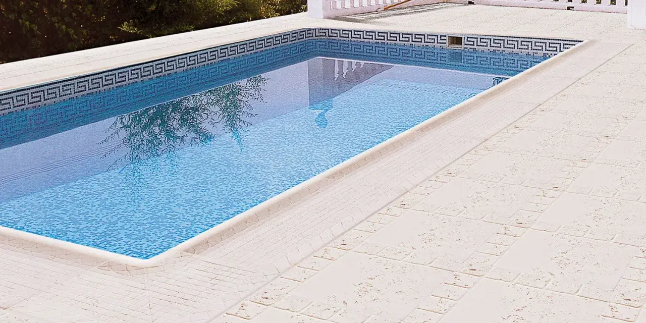 Piscina con borde de mosaico y suelos para piscinas que no quemen, de color claro y textura agradable.