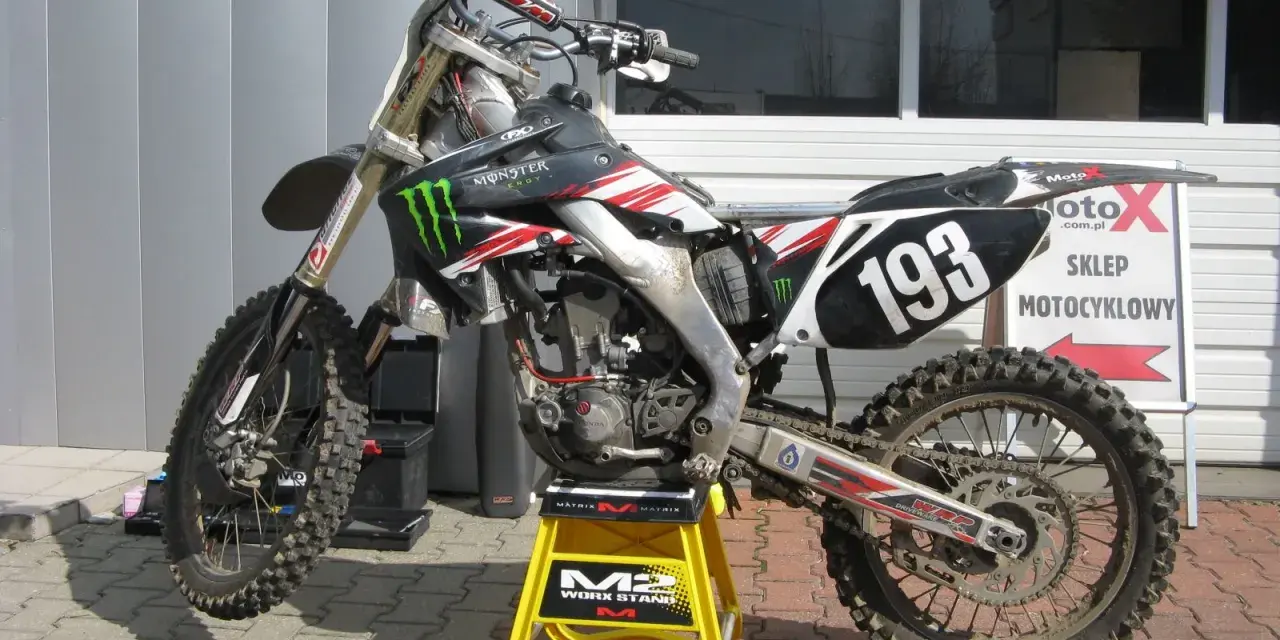 Motocykl crossowy na stojaku. Pytanie: co ile wymieniać filtr powietrza w motocyklu? Regularna konserwacja to klucz do mocy!