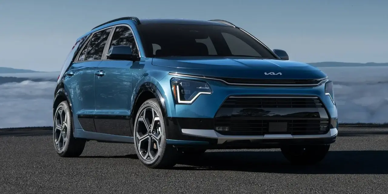 Niebieski Kia Niro Hybrid z nowoczesnym designem, zaparkowany na tle mglistego krajobrazu.