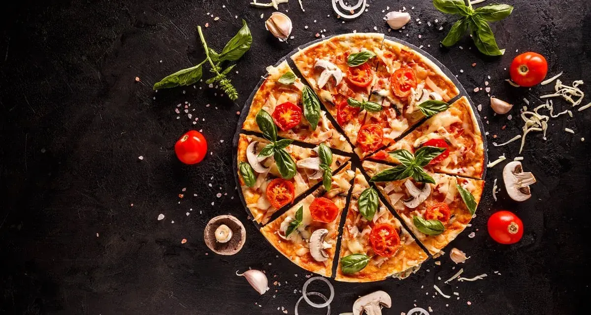 Pyszna pizza z pomidorkami, pieczarkami i bazylią. Zastanawiasz się, ile kcal ma pizza? To zależy od składników!