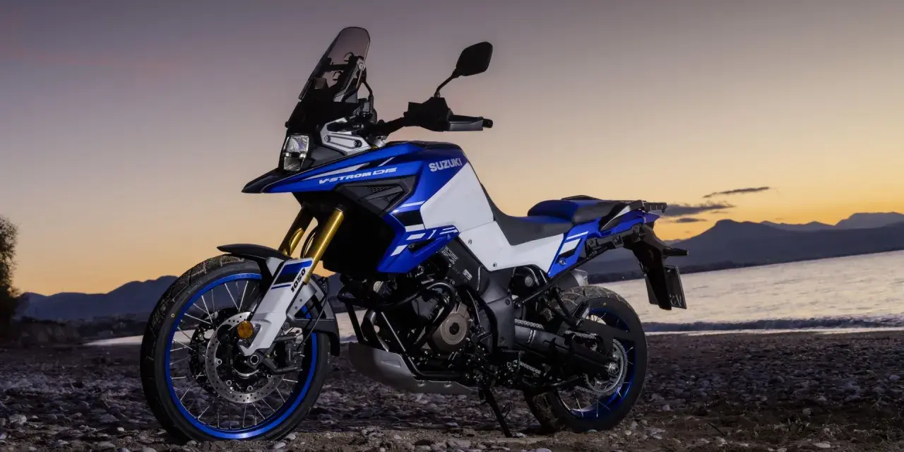 Suzuki V-Strom 1050 DE blu e bianca su una spiaggia al tramonto. Le opinioni su questa moto sono unanimi: avventura pura.