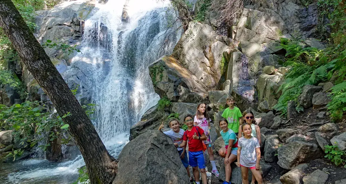 Niños exploran la Garganta de las Nogaleas, disfrutando de una cascada y la naturaleza.