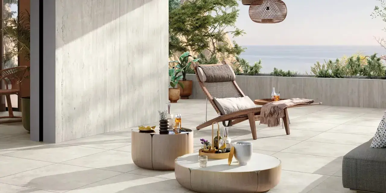 Une **terrasse en travertin** aux tons clairs, avec mobilier de détente et vue mer. Avis : un espace paisible et élégant.