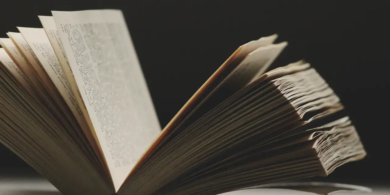 Un libro abierto revela páginas llenas de texto, evocando la sabiduría y las **frases en francés de la vida** que inspiran.