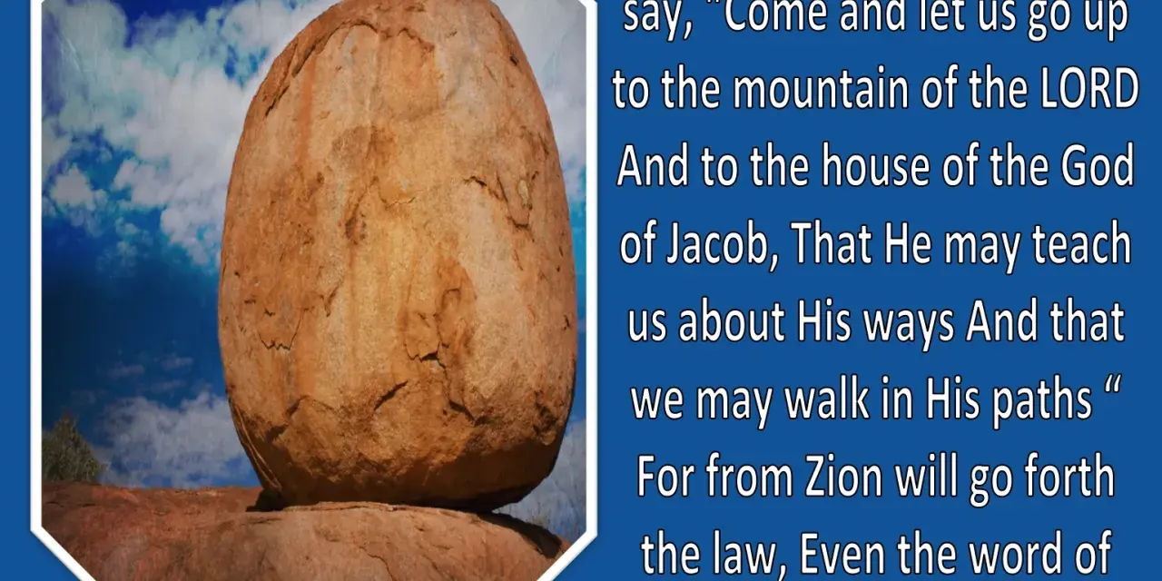 A large, weathered boulder rests precariously on smaller rocks under a blue, cloudy sky, illustrating a verse from Micah in the Bible.