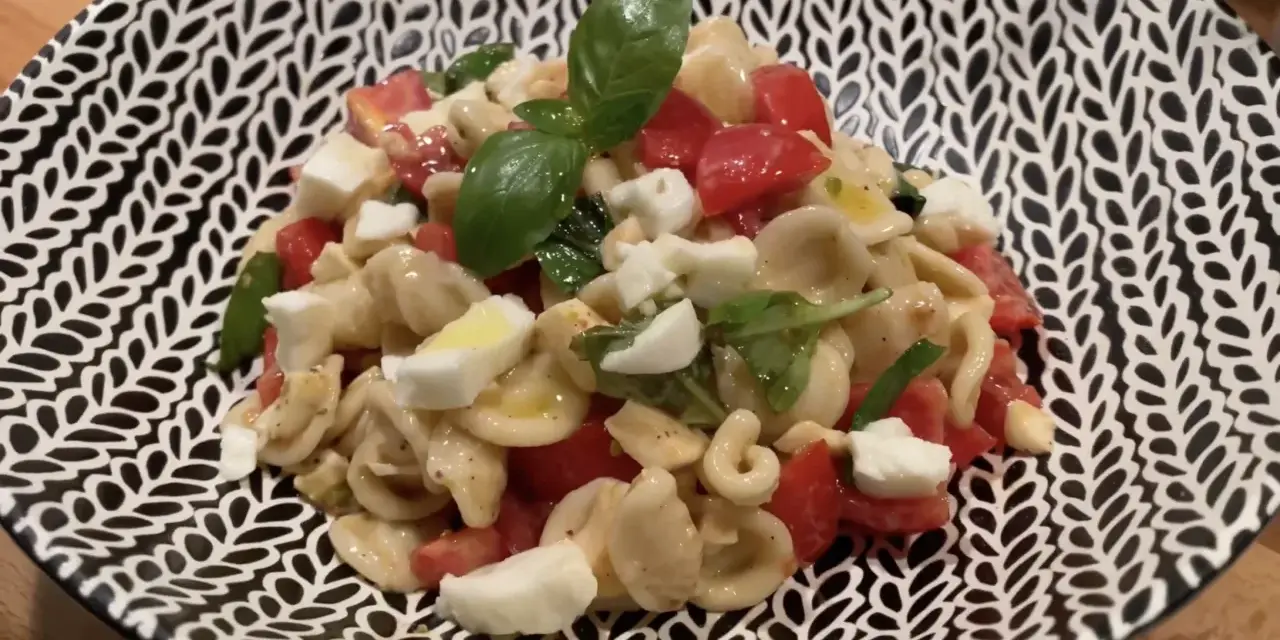 Orecchiette alla crudaiola con pomodorini, mozzarella e basilico fresco, un piatto estivo colorato e saporito.
