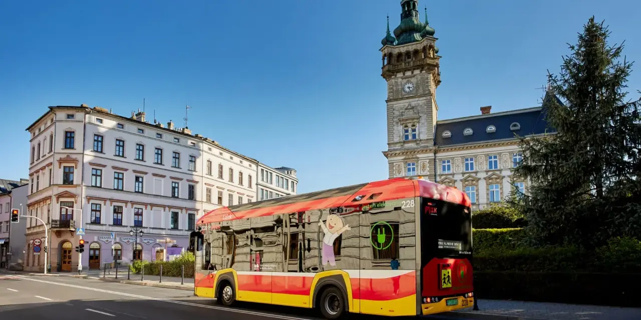 Autobus MPK Bielsko Biała z wizerunkiem uśmiechniętej postaci i zieloną wtyczką. Sprawdź rozkład jazdy MPK Bielsko Biała!