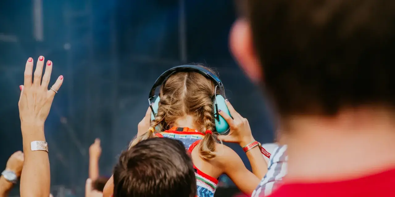 Une jeune fille aux tresses bleues porte un casque anti-bruit pour contrôler le niveau sonore d'un concert.