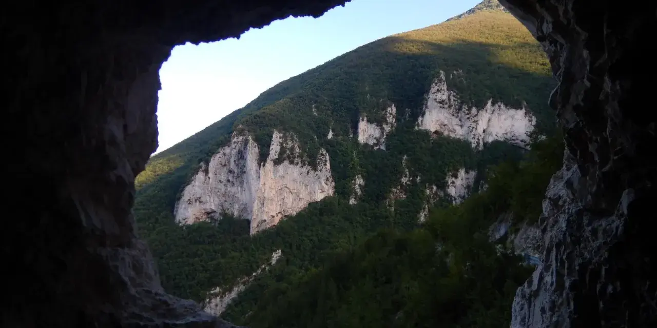 Vista dalla **grotta nera** su un monte verdeggiante con rocce bianche affioranti.