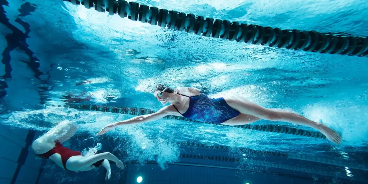 Deux nageuses en action, l'une effectuant une culbute natation, l'autre nageant le crawl sous l'eau.
