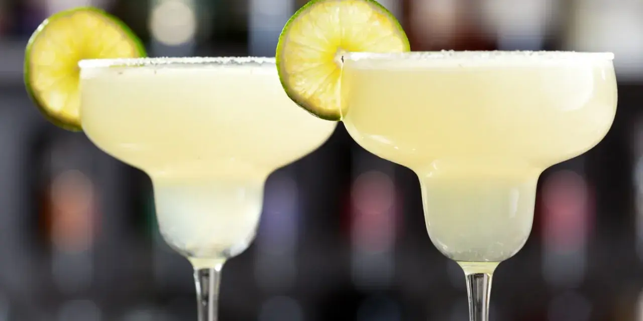 Två frostiga frozen margaritas med saltkant och lime, redo att avnjutas.
