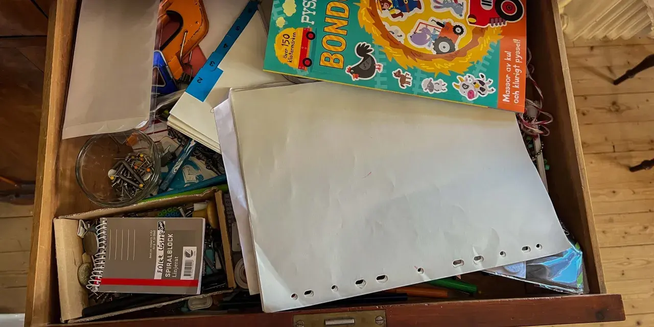 En låda fylld med pysselmaterial, papper, en bok med bondgårdstema och klistermärken, samt en burk med nålar och **påsklämmor**.