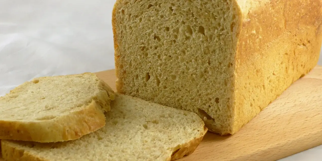 Frisch gebackenes Brot, das wie aus Buchweizen und anderen Getreidesorten gemacht aussieht, liegt auf einem Holzbrett.