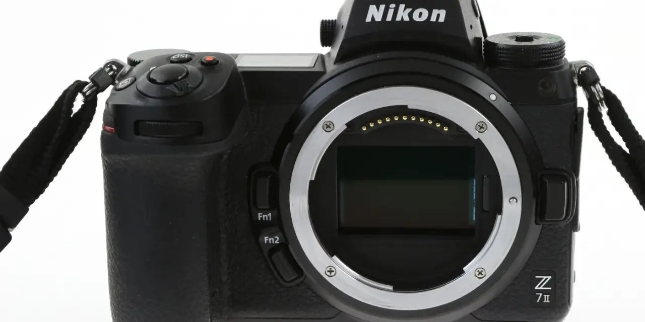 Czarny aparat Nikon Z7 III z obiektywem bez obiektywu, widoczny z przodu, z paskiem na nadgarstek.