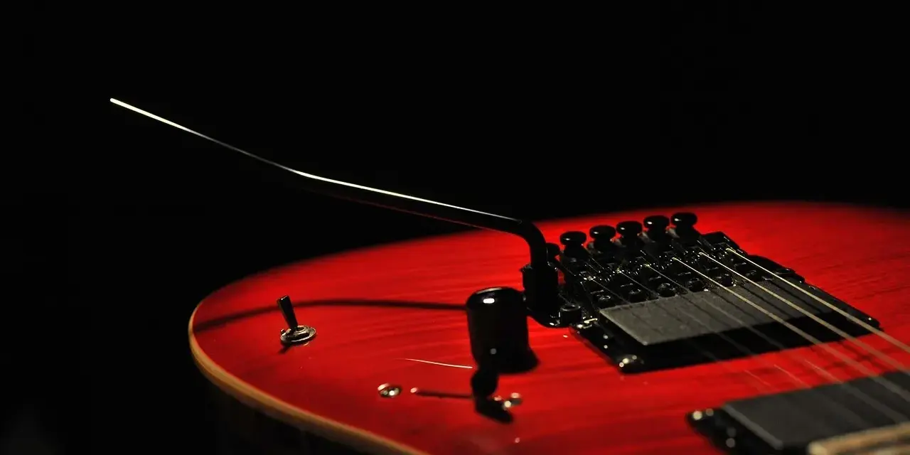 Czerwona gitara elektryczna z czarnym mostkiem tremolo, gotowa do wydobycia dźwięków, które poruszą serce.