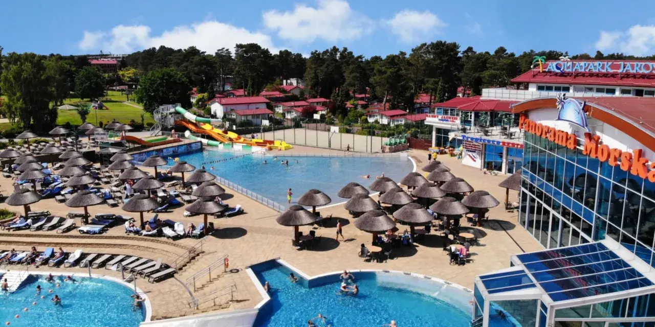 Aquapark w Jarosławcu: baseny, zjeżdżalnie i leżaki pod parasolami. Wiele osób korzysta z atrakcji, tworząc radosną atmosferę.