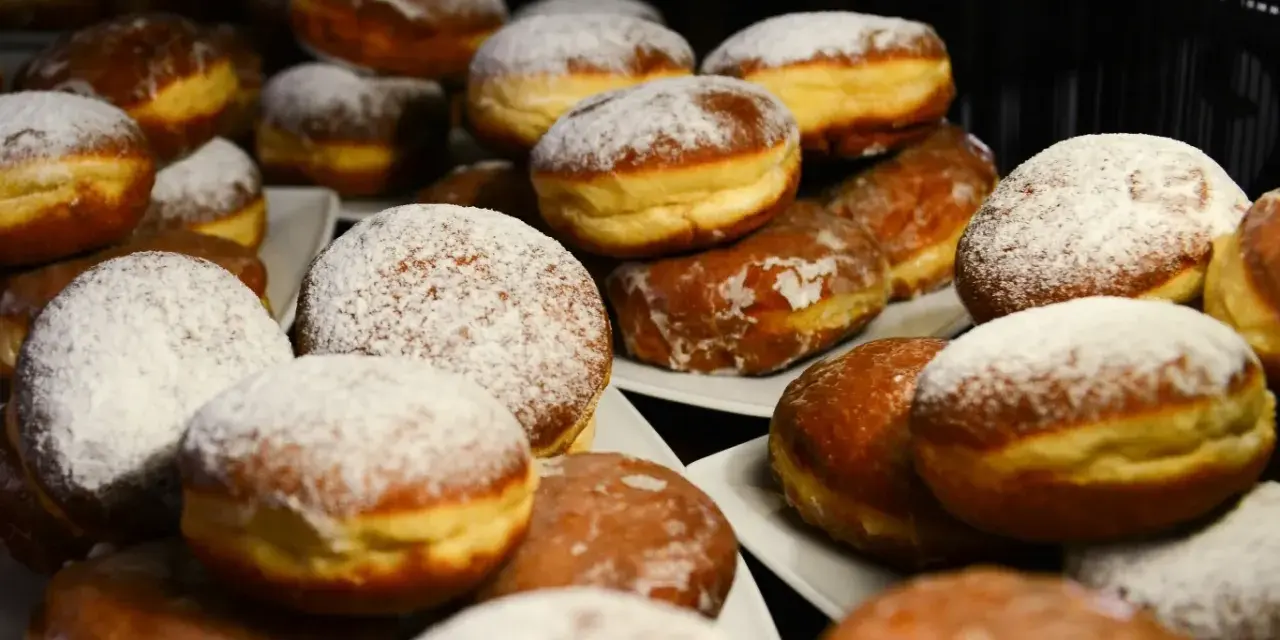 Puszyste pączki z piekarnika, niektóre oprószone cukrem pudrem, inne błyszczące od lukru. Idealne na tłusty czwartek!