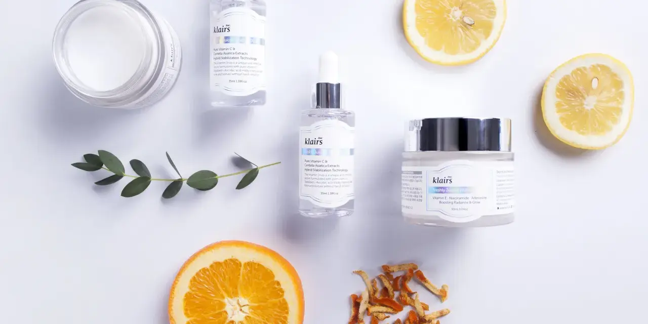 Hudvårdsprodukter från Klairs med C-vitaminserum och en kräm med e-vitamin hud för lyster. Citron- och apelsinskivor som dekoration.