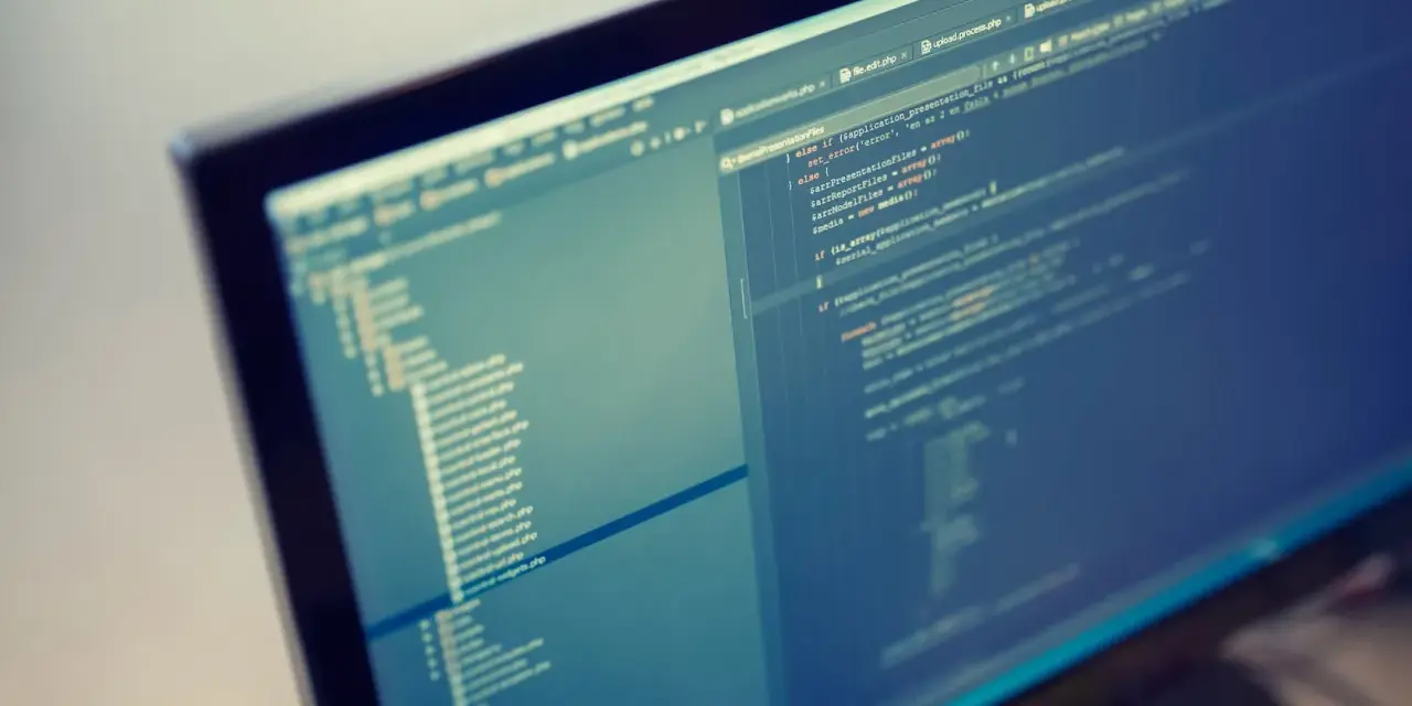 Programista pracuje nad kodem PHP. Format komputera pozwala na szybkie tworzenie i edycję skomplikowanych projektów.