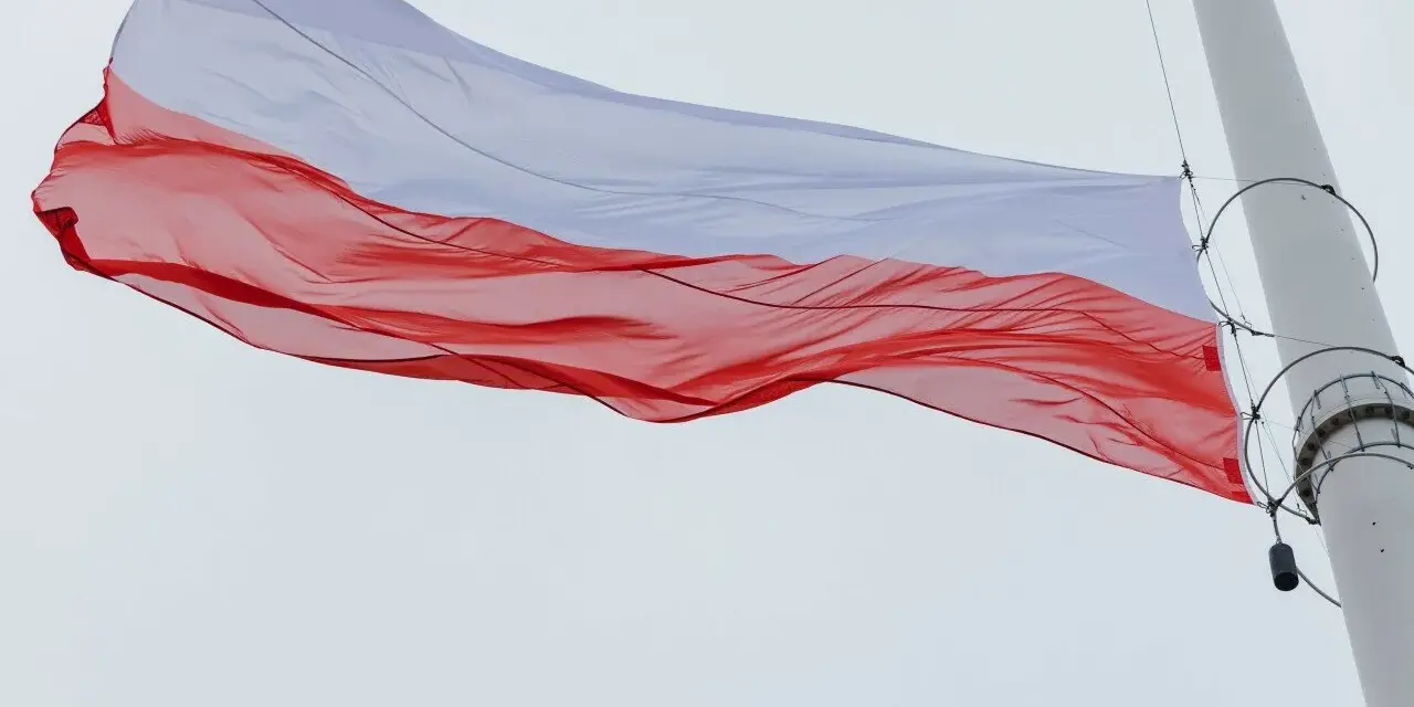 Biało-czerwona flaga na maszcie powiewa na wietrze, symbolizując dumę i wolność.