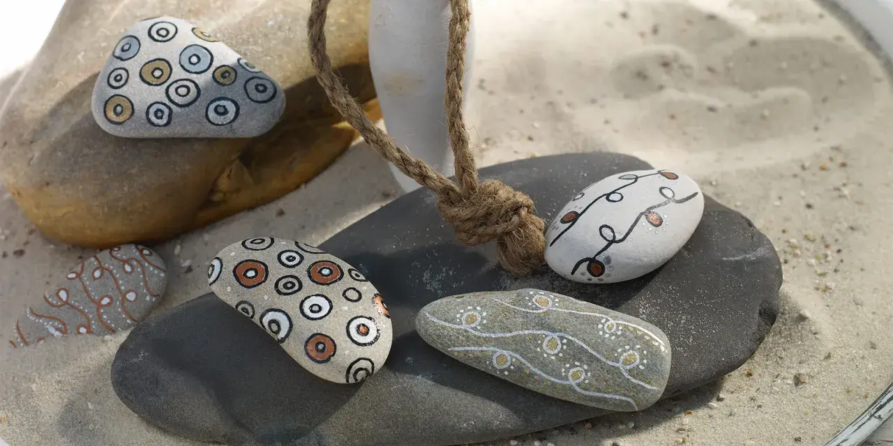 Piedras decoradas con rotuladores, creando patrones circulares y líneas onduladas. Un detalle artesanal para coleccionar.