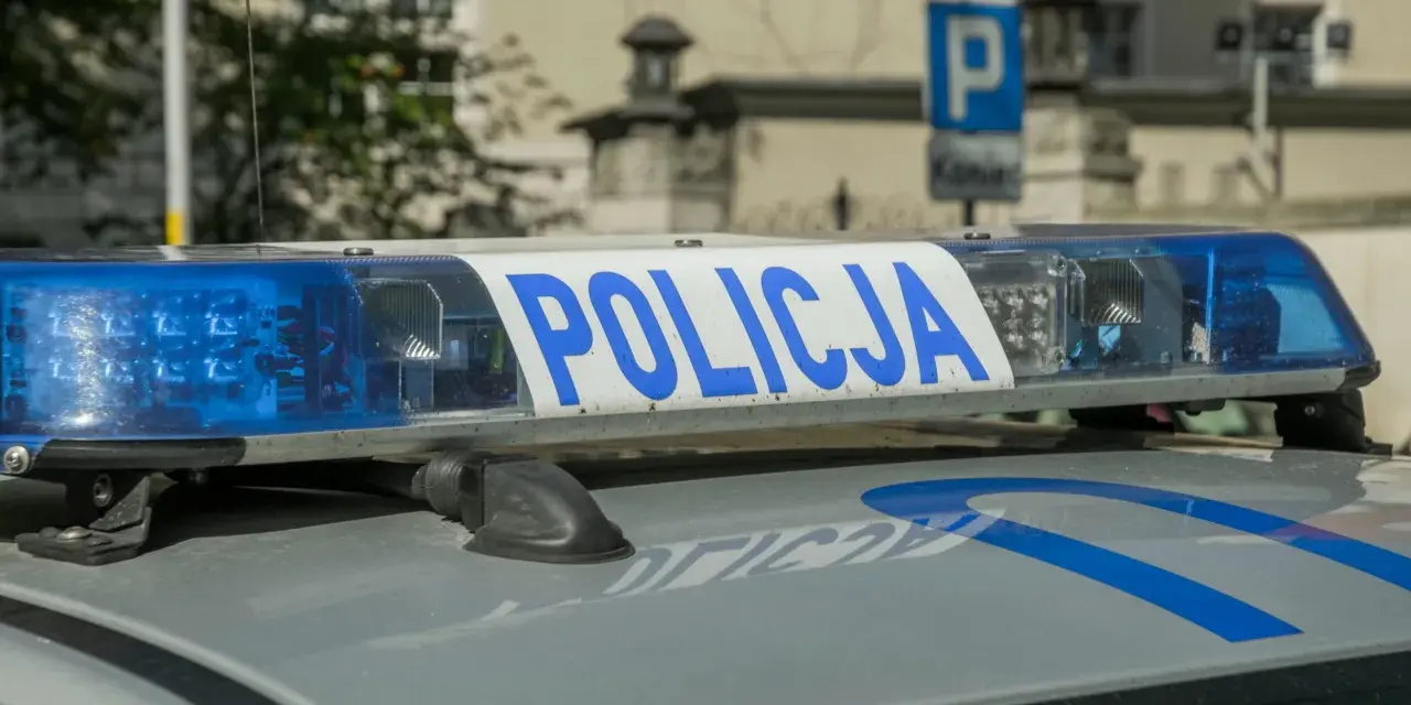 Niebieskie światła policyjne i napis "POLICJA" na dachu radiowozu. Uważaj na przegląd, bo czeka mandat za brak przeglądu.