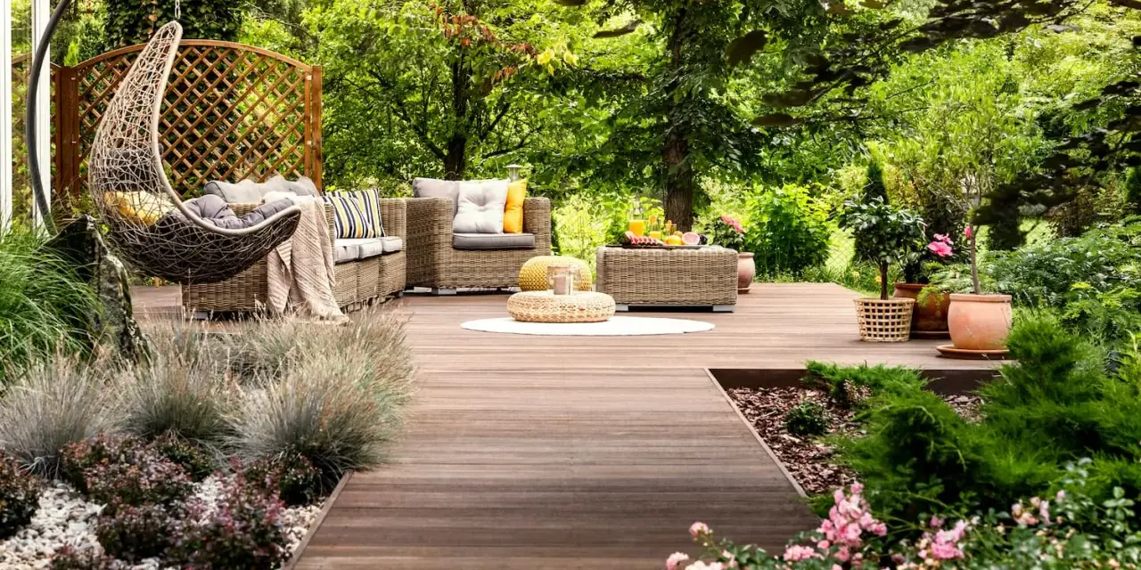 Un rincón acogedor con muebles de mimbre, una hamaca colgante y flores, ideal para disfrutar de pequeños jardines.