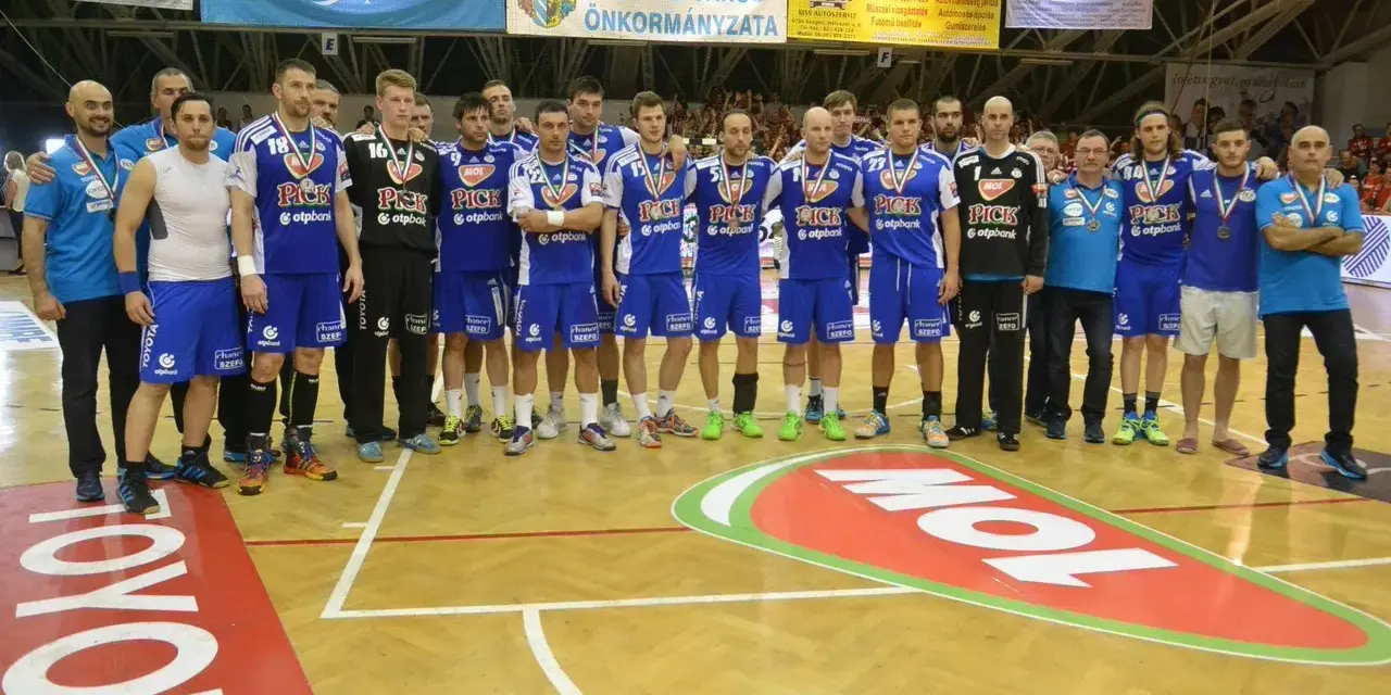 Drużyna piłkarzy ręcznych PICK Szeged w niebieskich strojach pozuje do zdjęcia po meczu.