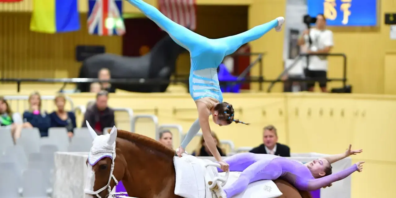 Deux gymnastes réalisent une performance de gymnastique cheval. L'une est en équilibre sur les mains, l'autre allongée sur le dos du cheval.