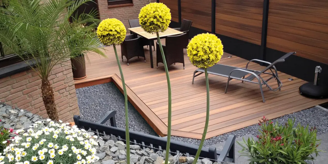 Giardino moderno senza erba: deck in legno, ghiaia, piante in vaso e fiori bianchi. Esempi idee giardino senza erba.