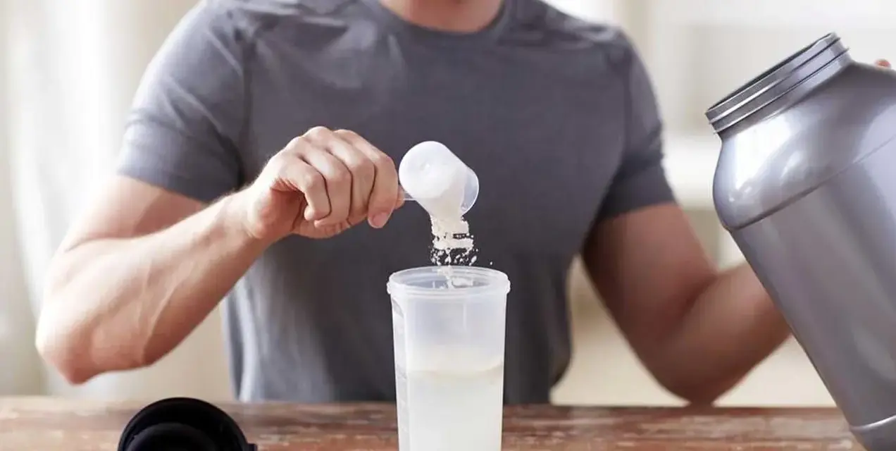 Hombre preparando un batido. Sabe cuándo tomar BCAA para optimizar su entrenamiento.