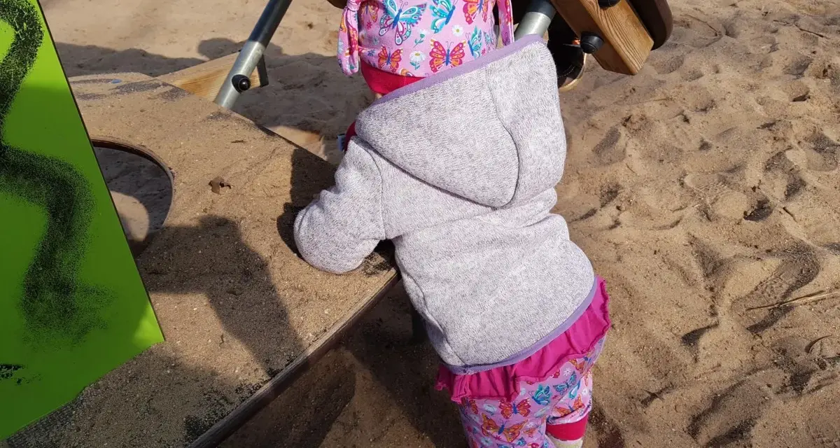 Kleines Kind auf dem Spielplatz, das die Welt erkundet. Manchmal sind die Nachteile der bindungsorientierten Erziehung, dass Kinder sich schwerer lösen können.