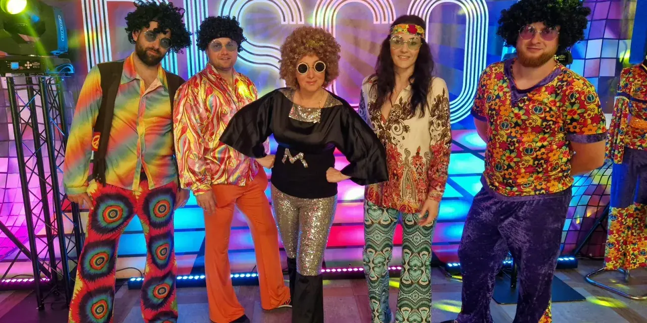 Pięć osób w kolorowych strojach disco z lat 70. na tle napisu "DISCO".