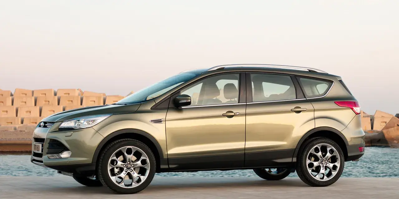 Złoty SUV Ford Kuga stoi na nabrzeżu przy morzu.