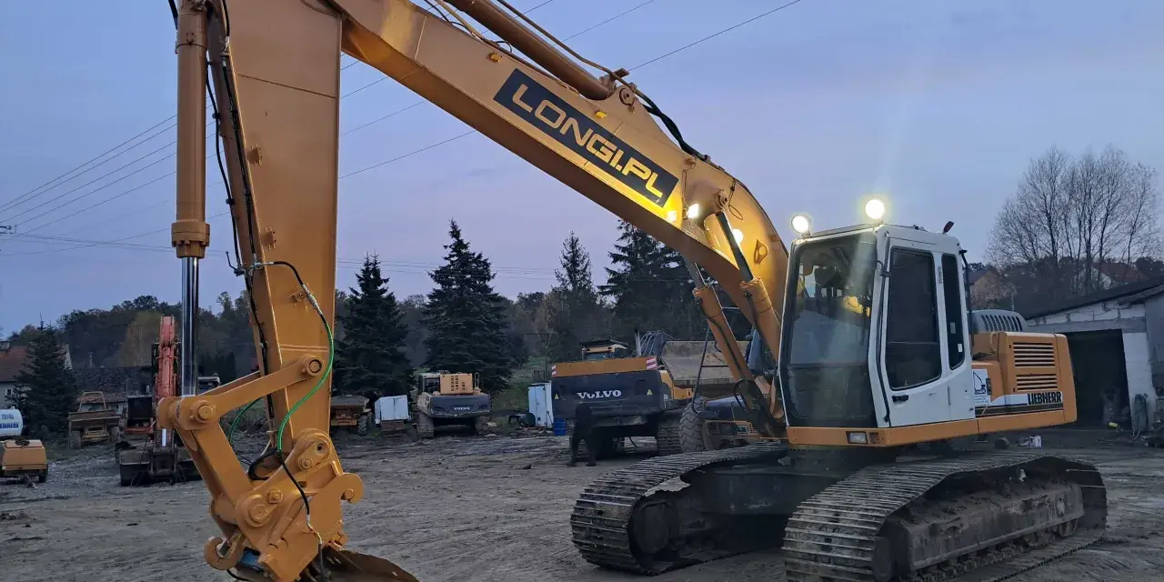 Żółta koparka gąsienicowa Liebherr z napisem LONGI.PL gotowa do pracy. Dostępna do wynajęcia.