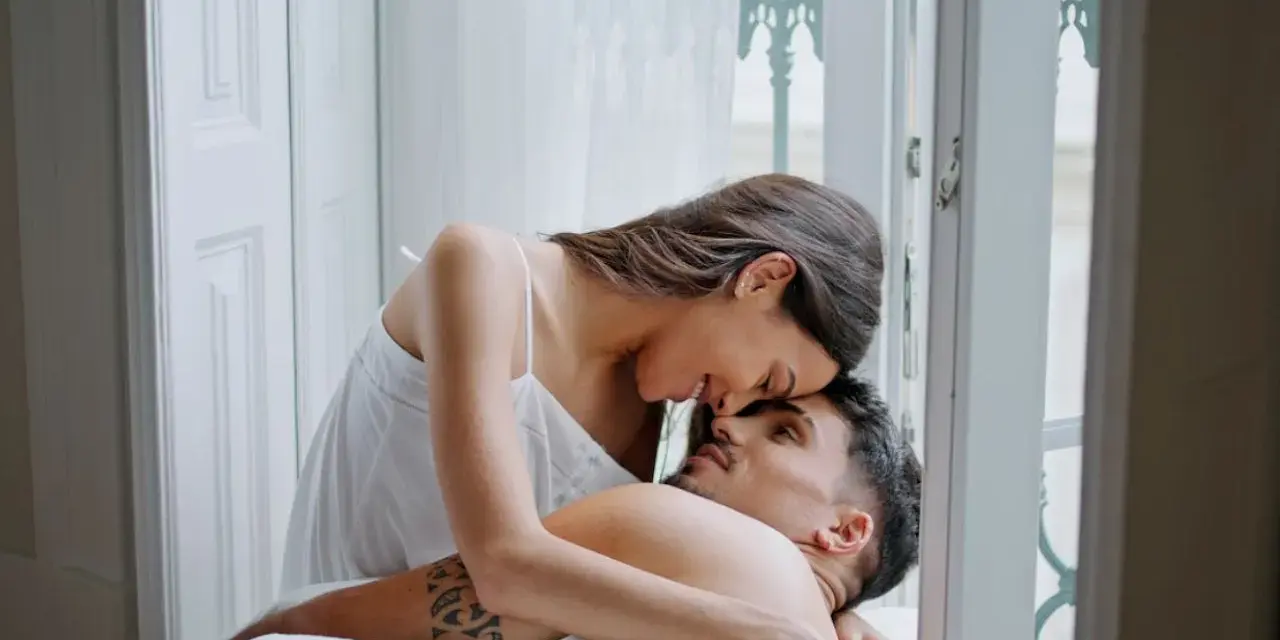 Para zakochanych w łóżku, czułe spojrzenia i dotyk. Słodki, waniliowy seks w blasku poranka.