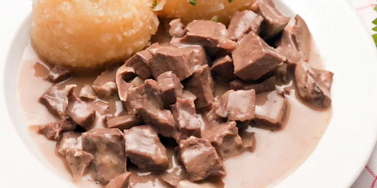 Saure Lunge in cremiger Soße mit Kartoffelklößen, garniert mit Schnittlauch. Ein herzhaftes Gericht, das an Omas Küche erinnert.
