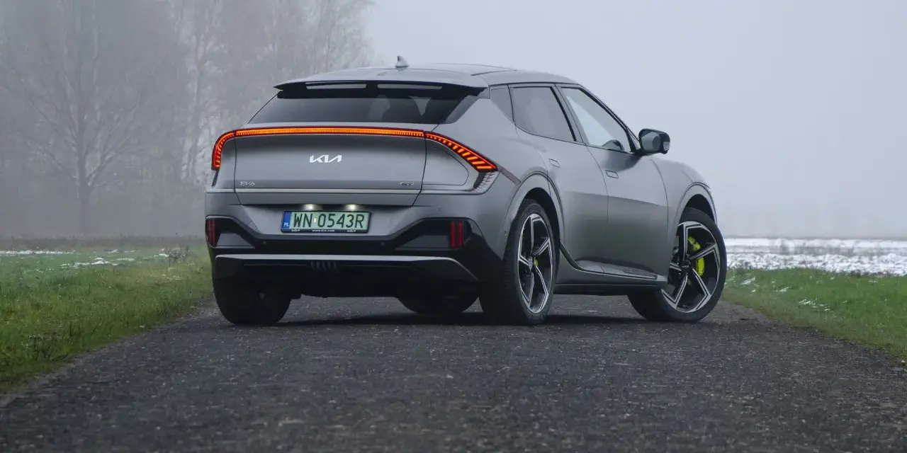 Szare Kia EV6 GT z żółtymi zaciskami hamulcowymi na tle mglistego krajobrazu.