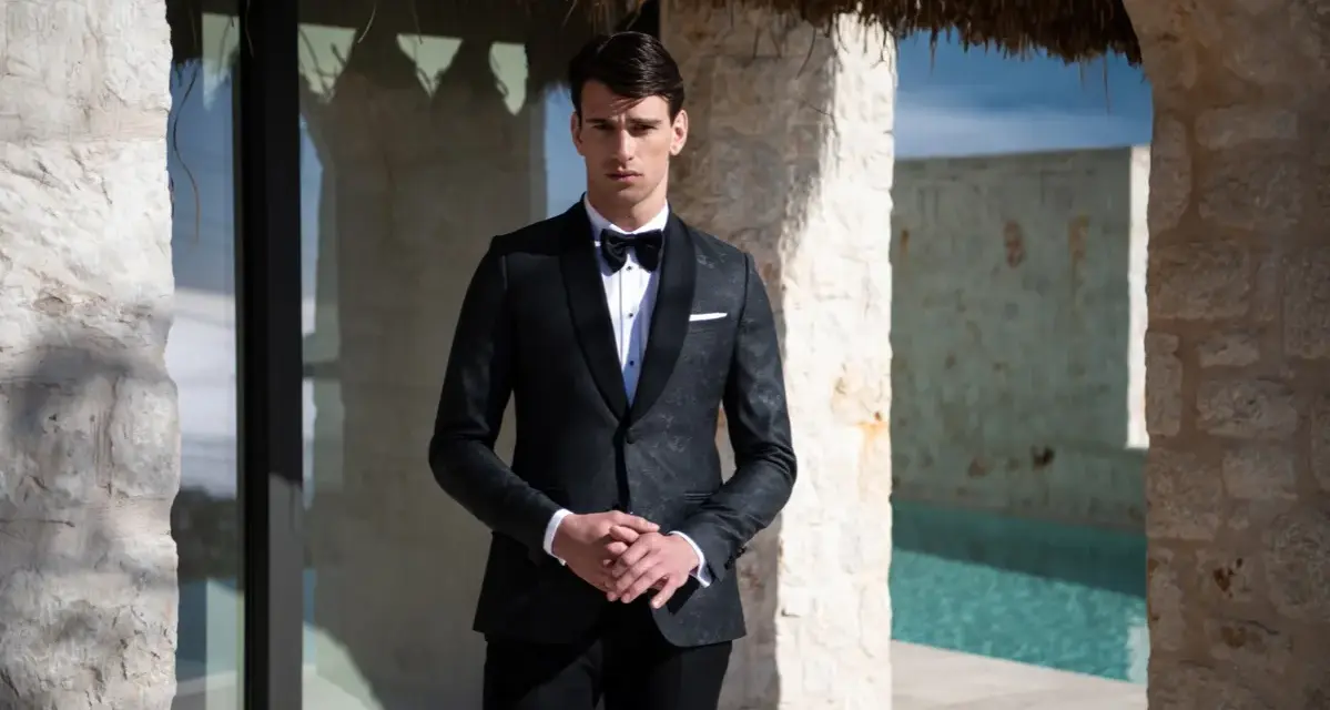 Elegancki mężczyzna w smokingu, idealny przykład stroju black tie na wesele. Różnica między ubiorem black tie a cocktail dress dla gości weselnych jest widoczna.