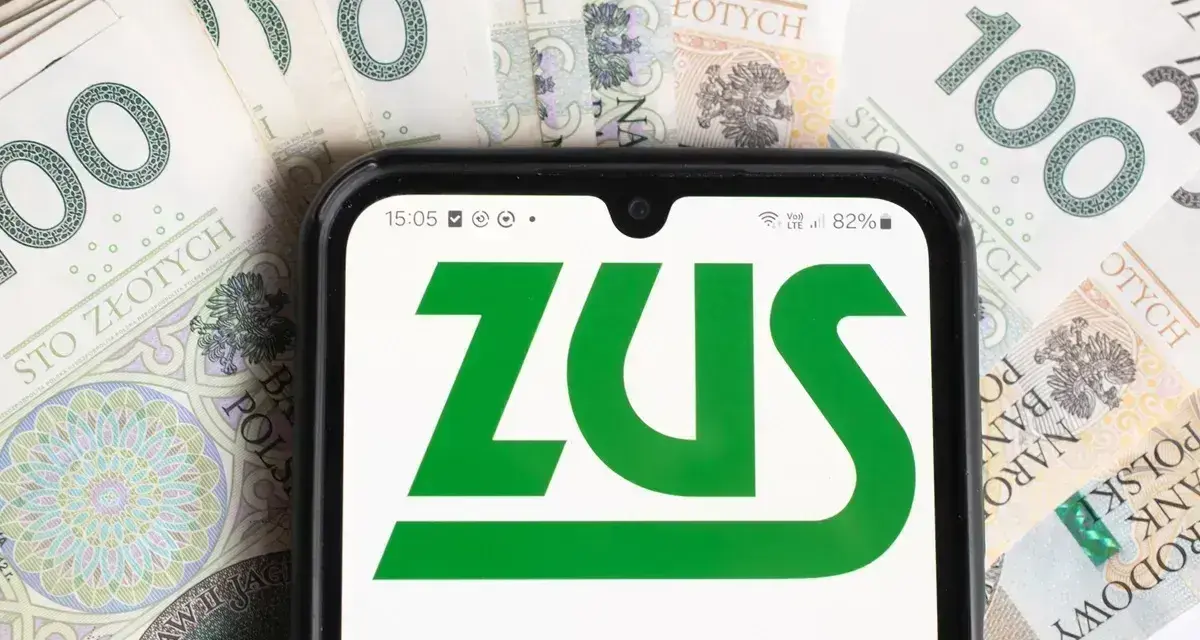 Telefon z logo ZUS na tle polskich banknotów 100 zł.