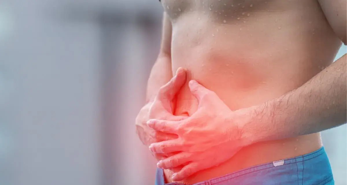 Homme tenant son ventre, zone rouge indiquant une douleur, possible déchireure abdominaux.