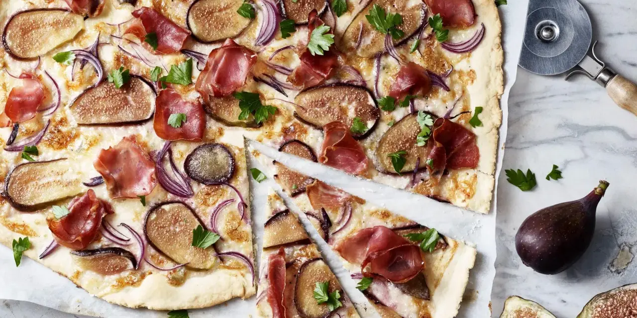 Ein köstlicher Flammkuchen mit Feigen, Schinken und roten Zwiebeln, garniert mit Petersilie.