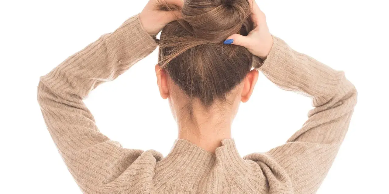 Manos arreglando un moño alto despeinado, perfecto para una boda.