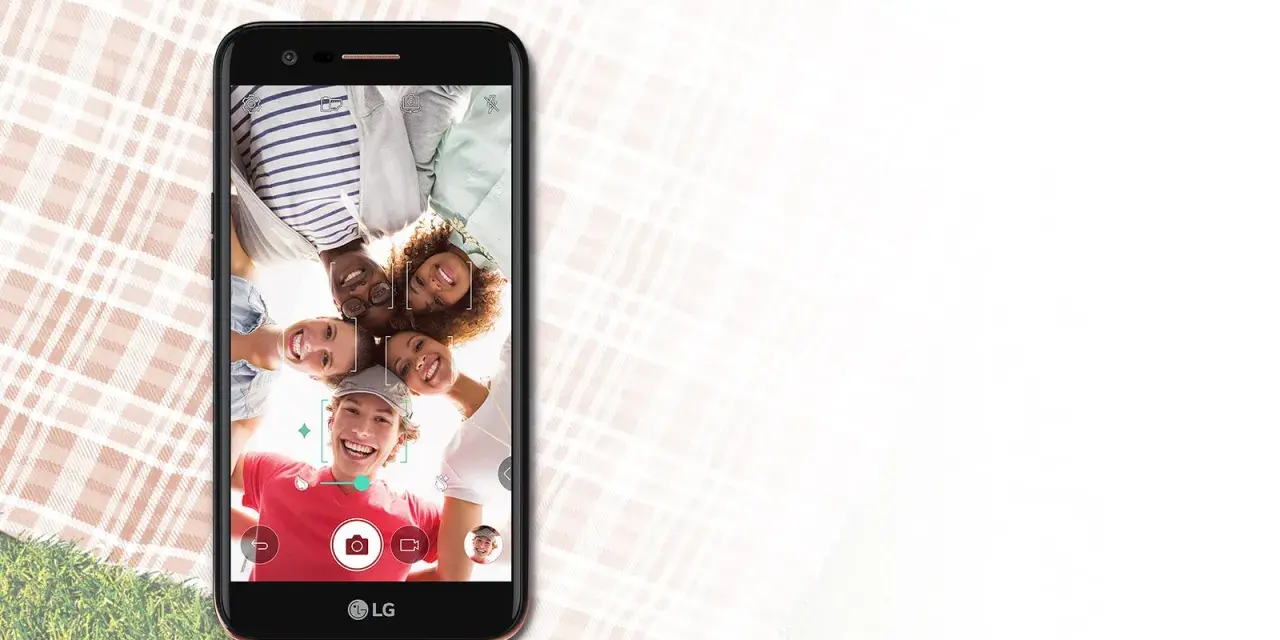 Uśmiechnięta grupa przyjaciół robi selfie telefonem LG K10 2017 Dual na pikniku.