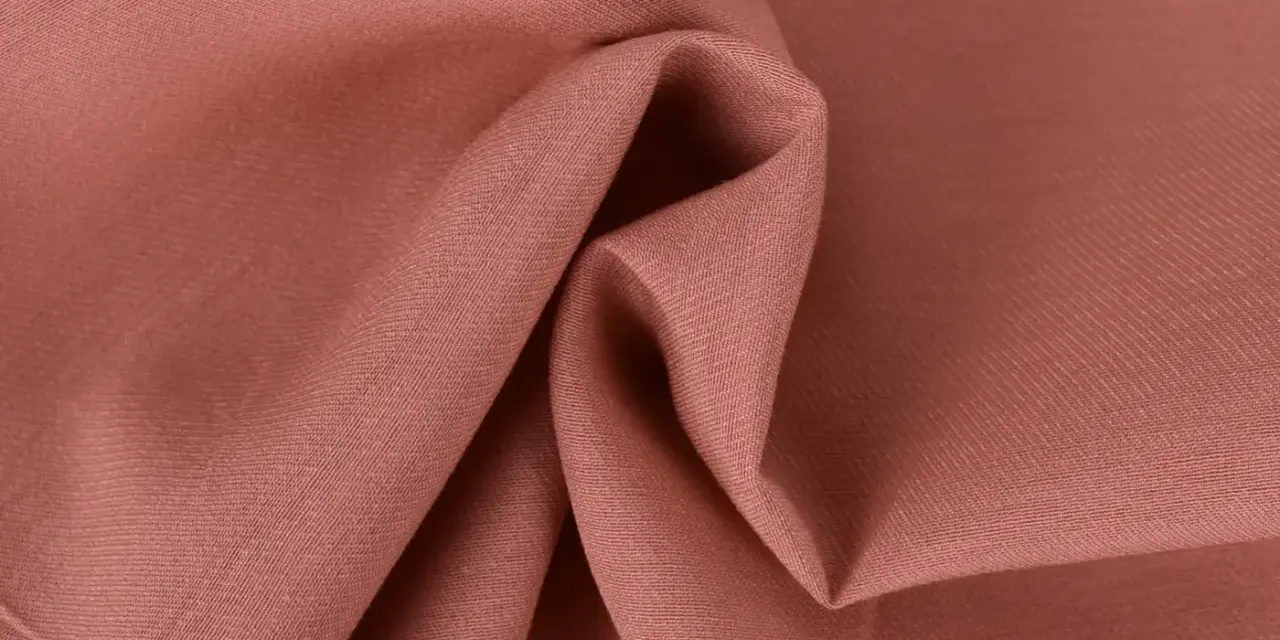 Tessuto twill color salmone, ideale per capi invernali o estivi, con pieghe morbide che ne esaltano la trama.
