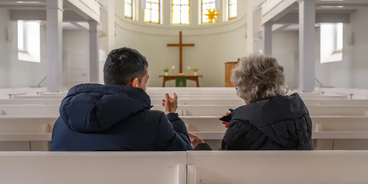 Zwei Menschen im Gespräch in einer Kirche, ein Symbol für die Verbindung von Kirche und Gesellschaft.