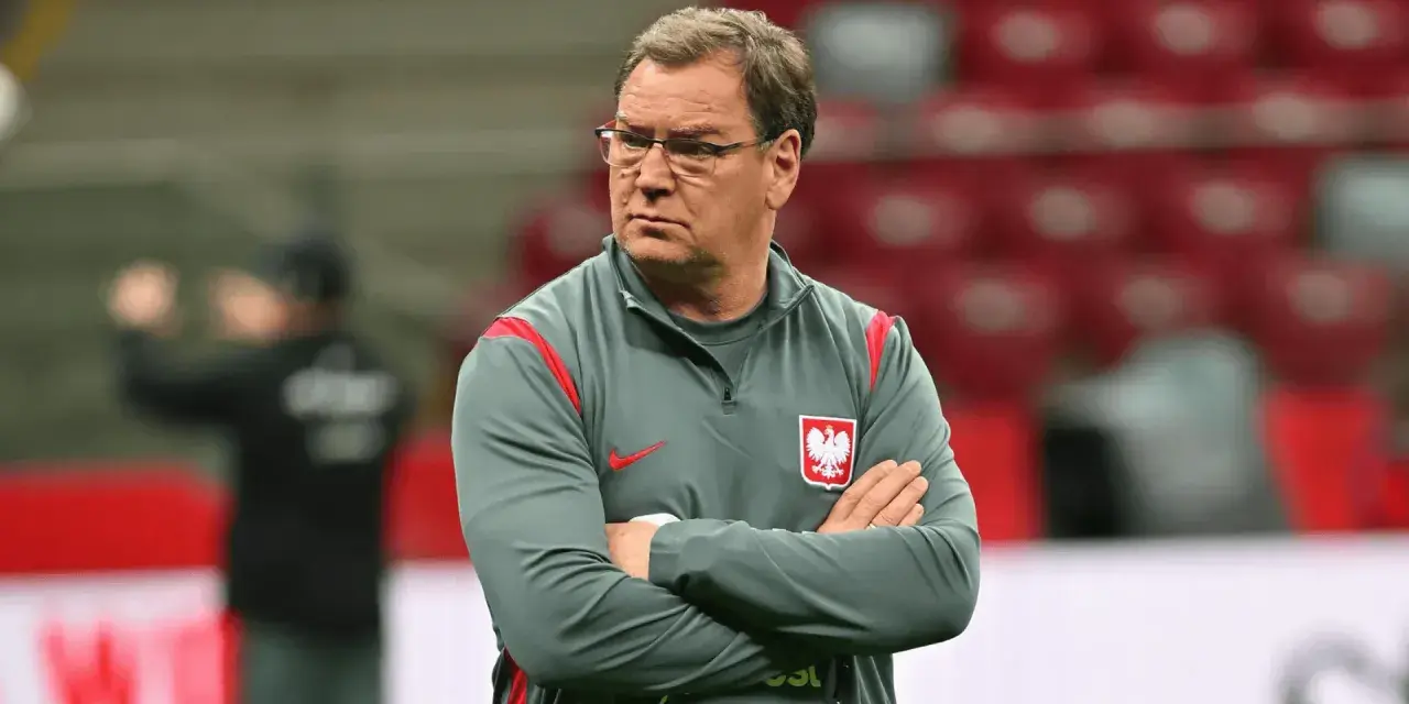 Trener reprezentacji Polski w piłce nożnej, z założonymi rękami, w okularach, zastanawia się, ile zarabia.
