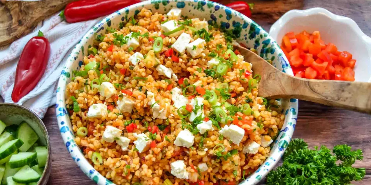 Frischer bulgursalat mit feta, Tomaten, Paprika und Frühlingszwiebeln, garniert mit Petersilie.