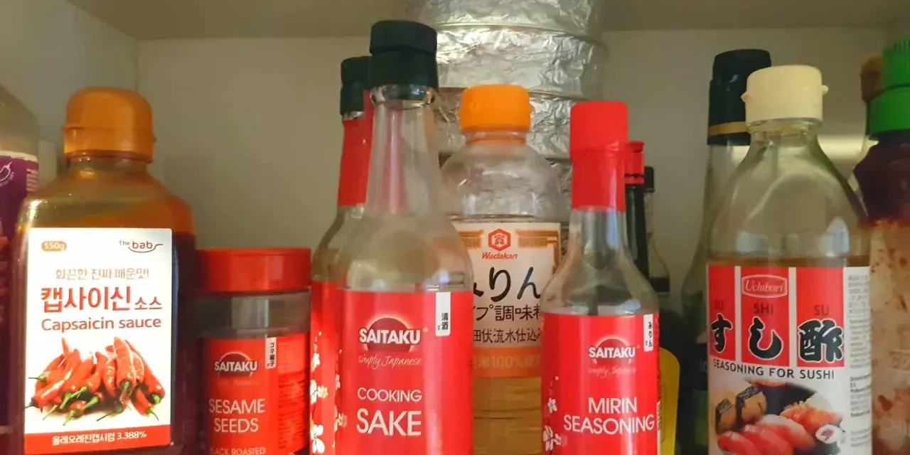 Butelka z napisem "MIRIN SEASONING" obok sosu do sushi i sake. Mirin co to? To japońska przyprawa do gotowania.