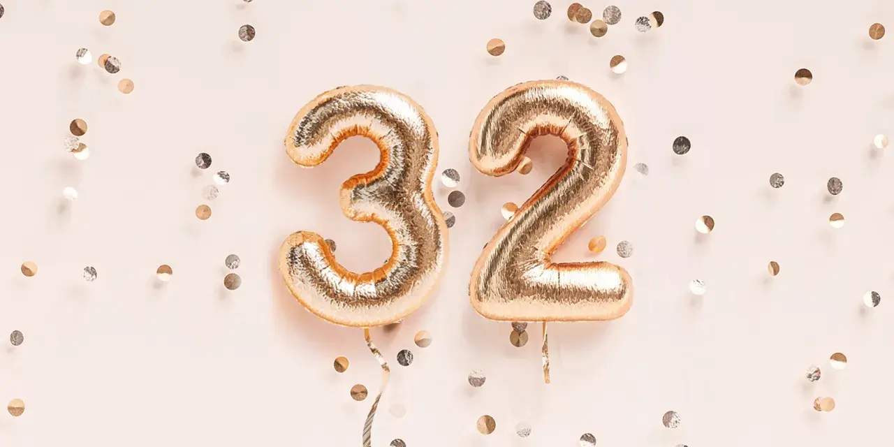 Złote balony z cyframi 3 i 2, otoczone konfetti. To już 32 tydzień ciąży, który to miesiąc?